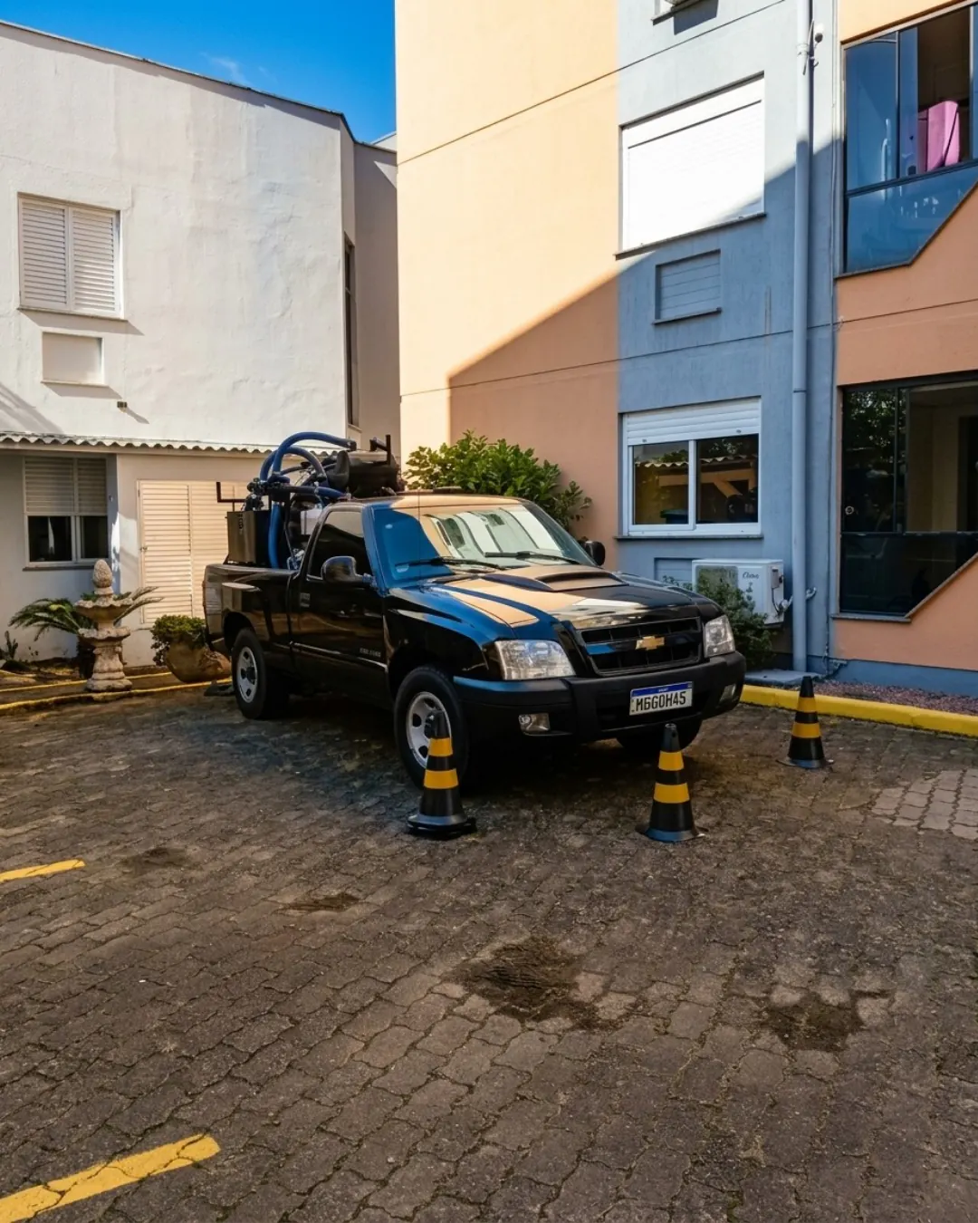 Picape preta com equipamento móvel de hidrojateamento em condomínio